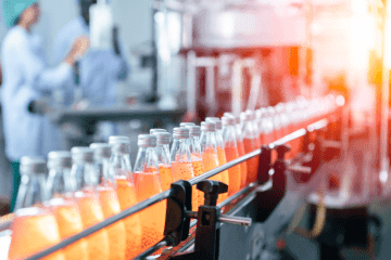 Photo of a Food and Drink Manufacturing conveyor belt, showing bottles of orange drink
